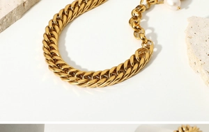 Detail of 18K gold plated Cuban chain bracelet with freshwater pearl on stone texture