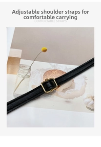 Detail of adjustable black leather shoulder strap with gold-tone buckle for handbag
