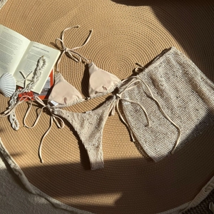 Detailed flat lay of beige crochet three-piece bikini set with matching beach skirt