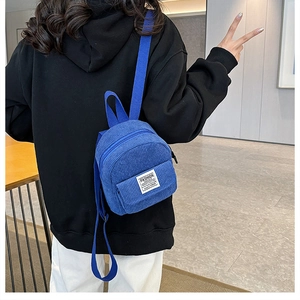Detail view of bright blue corduroy mini backpack with adjustable straps on model