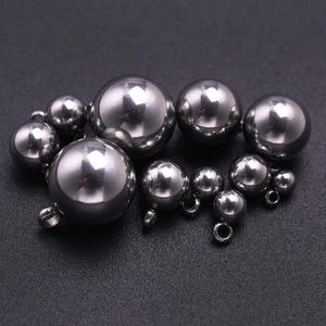 Détail macro de pendentifs boules en acier inoxydable poli avec anneaux sur fond texturé