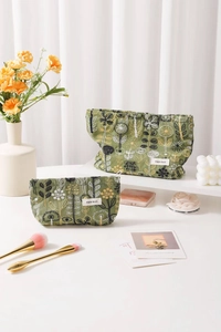 Detailed view of two green linen bags with floral embroidery and white brand label