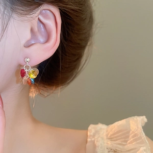 Close-up of colorful beaded tassel earrings on a model with vibrant faceted resin beads