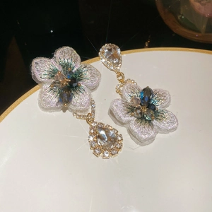 Dettaglio orecchini a fiore ricamati con cristalli a goccia ed effetto brillante a stella