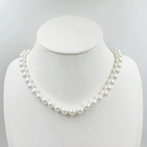 Macro view of white round shell pearl necklace on a textured neck mannequin