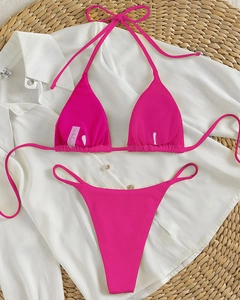Detailed view of pink ribbed bikini set with halter top and thong bottoms on beach mat
