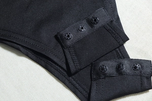 Close-up of black plastic snap buttons on a knitted fabric texture of a women's outfit