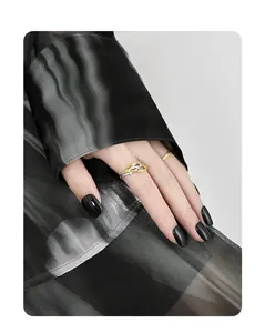 Macro detail of S925 silver thorn ring and gold band on fingers against dark fabric