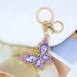 Dettaglio portachiavi a farfalla con cristalli viola e strass luccicanti su metallo