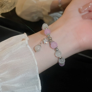 Detailed view of beaded star bracelet with pink cat eye stones and silver star charm