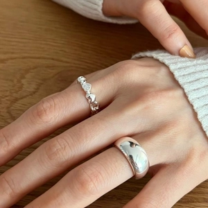 Close-up of a silver heart-shaped ring paired with a polished dome ring on fingers