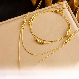 Close-up of gold layered chain jewelry set with metallic beads and imitation pearls
