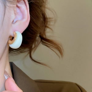 Close-up of model wearing 18k gold plated resin C-shape hoop earrings in white