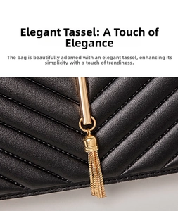 Detail of V-quilted black leather surface with gold metal tassel pendant on small handbag