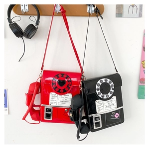 Detailed view of red and black glossy telephone shaped crossbody bags on a display rack