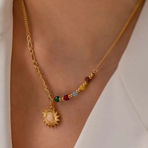 Detail of bohemian gold sun pendant necklace with colorful beads on an asymmetric chain