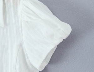 Detail of white puff sleeves featuring delicate vertical striped translucent texture