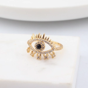 Macro shot of gold evil eye ring featuring crystal pavé details and a black stone center