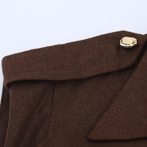 Détail de la texture en lin de la robe midi marron foncé avec bouton décoratif doré