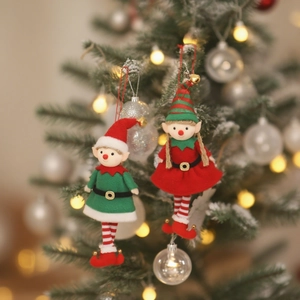 Christmas elf plush ornaments with bells hanging on a decorated tree with warm lights