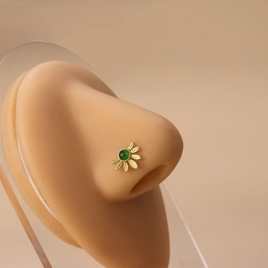 Gold flower nose stud with green stone and leaf design on realistic silicone nose model