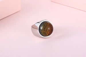 Macro detail of high-polished stainless steel ring with orange-black foil glass dome
