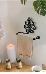 Detailed close-up of vintage black cast iron towel rack with elegant Fleur-de-lis patterns
