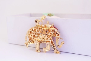 Macro view of a gold hollow elephant pendant with heart patterns and red accents