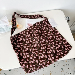 Detailed macro view of a brown corduroy tote bag with pink floral patterns and a tag