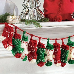 Knitted Christmas advent calendar socks in red green and white hanging on fireplace