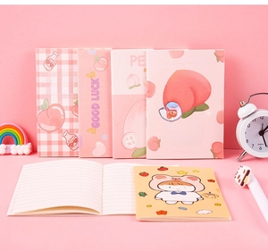 Detailed close-up of pink peach-themed notebooks with lined pages and cartoon stationery