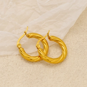 French style gold spiral twisted hoop earrings in stainless steel on a beige textured fabric