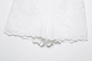 Dettaglio ravvicinato del ricamo in pizzo bianco e bordo ondulato dei pantaloncini