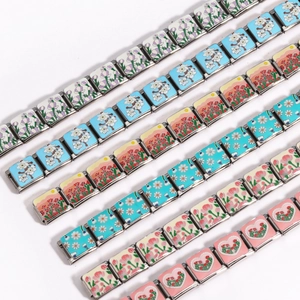 Close-up of modular Italian charm bracelets with floral enamel patterns on stainless steel