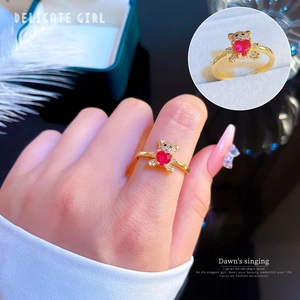 Close-up of gold bear ring holding a heart-shaped red zircon with micro-pave details