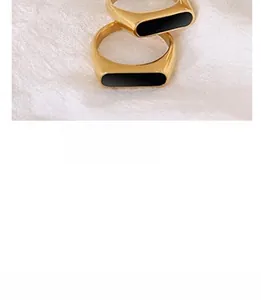 Detail of two minimalist gold-plated titanium steel rings with rectangular black enamel inlay