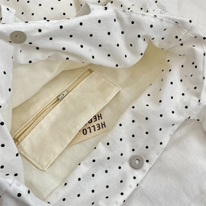 Detailed view of canvas tote interior with polka dot pattern and magnetic metal buckle