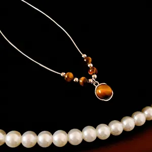 Collier avec pendentif en œil de tigre et chaîne argentée sur fond noir chic