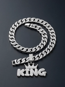 Detailed close-up of a silver Cuban link chain with a sparkling iced-out KING crown pendant