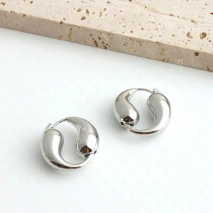 Polished silver teardrop hoop earrings displayed on a natural stone and white surface