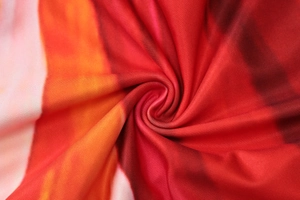 Detailed macro view of the warm-toned tie-dye knitted fabric with soft ribbed texture