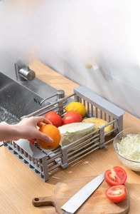 Close-up of extendable stainless steel sink rack holding fresh vegetables and fruits