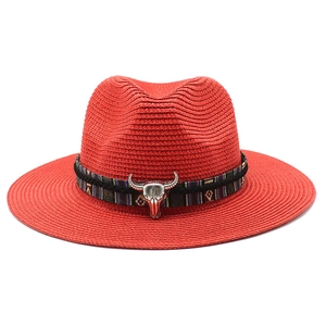 Dettaglio cappello di paglia rosso con nastro etnico e ciondolo testa di toro