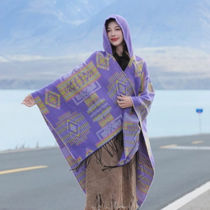 Ethnic knit hooded poncho with colorful geometric patterns and black fringe on lake road