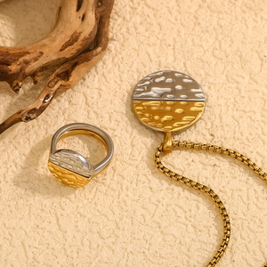 Detail of two-tone hammered metal jewelry set with ring and chain necklace