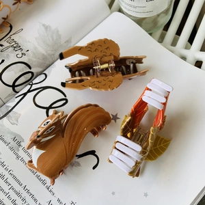 Detail view of animal-themed acetate hair claws featuring squirrel and leaf designs