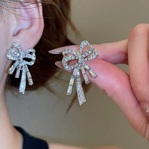 Detailed view of silver bow-shaped earrings with sparkling crystals and pearl accents