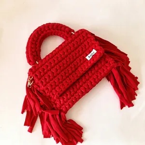 Close-up of handmade red crochet handbag featuring thick cotton tassels and texture