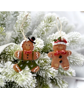 Detailopname van peperkoekman hangers aan een besneeuwde kerstboom als decoratie