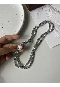 Detail of grey glass pearl double necklace featuring a square mother of pearl clasp